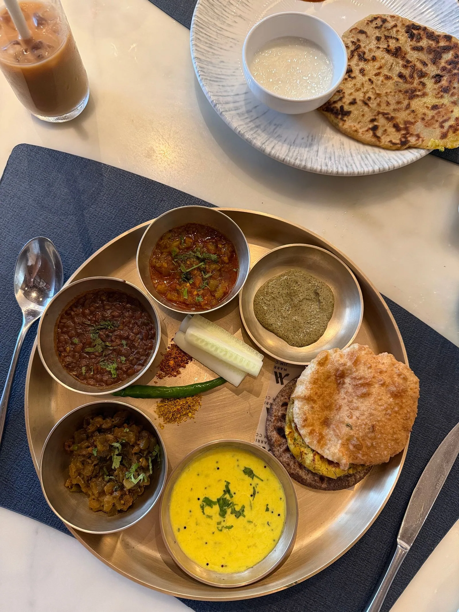 Vegetarian thali of dal, kadhi and vegetables in small steel bowls with flatbread on the side