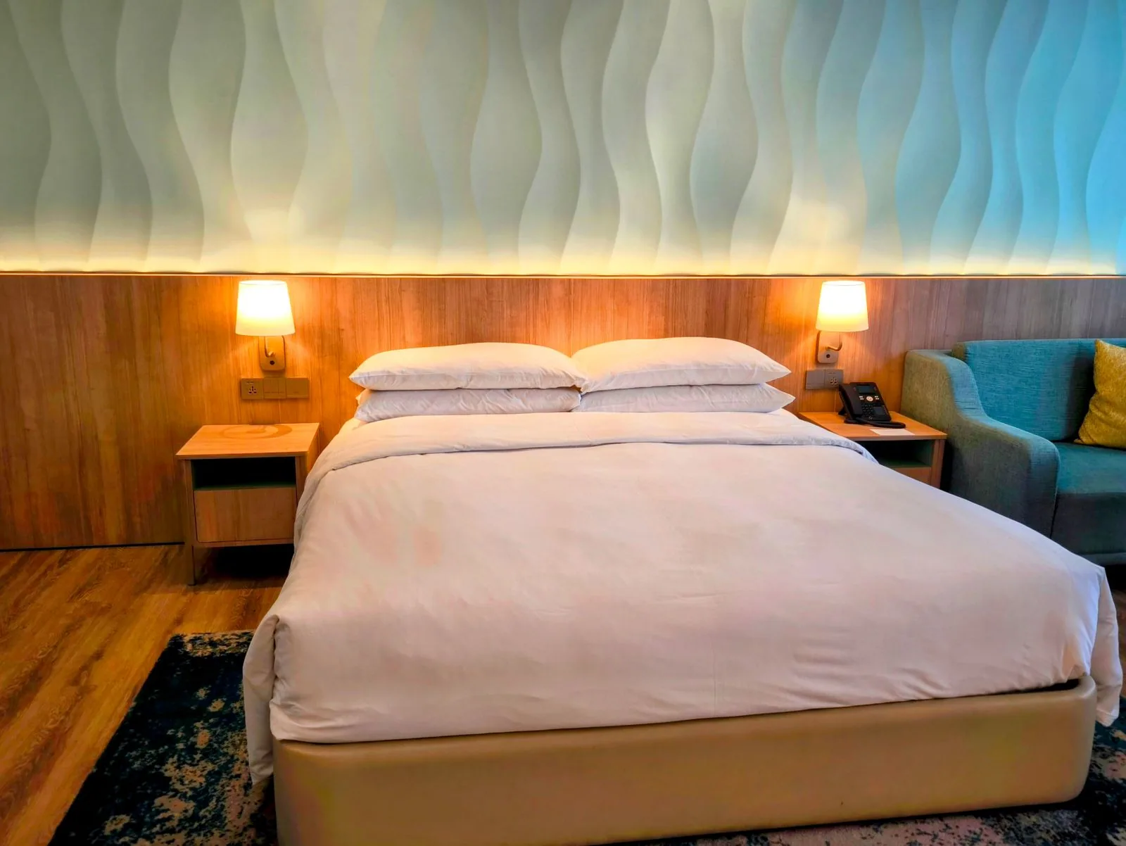 Double bed with white linen and two bedside lamps against a wood panelled wall